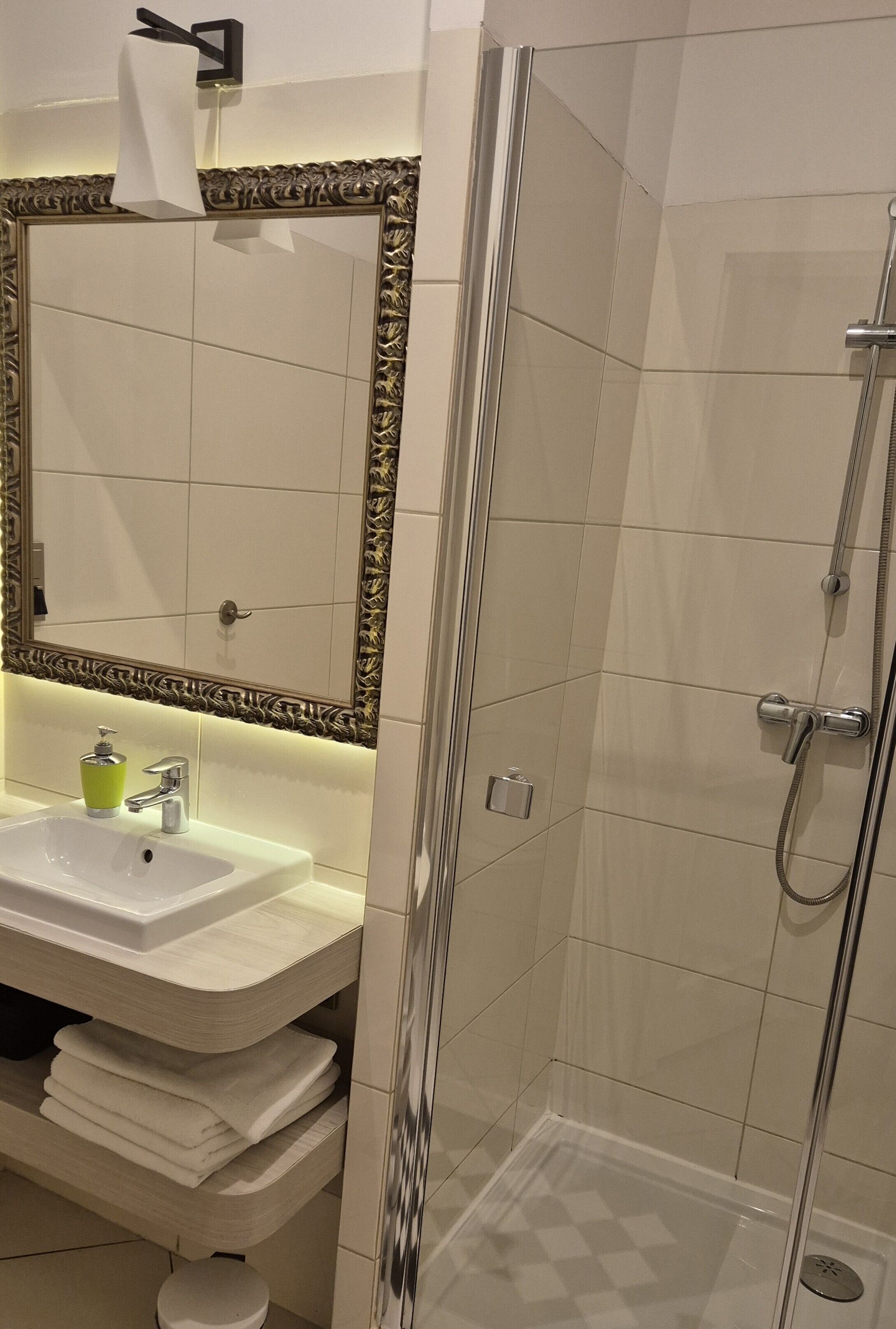 A bathroom with a white sink, mirror, and shower.