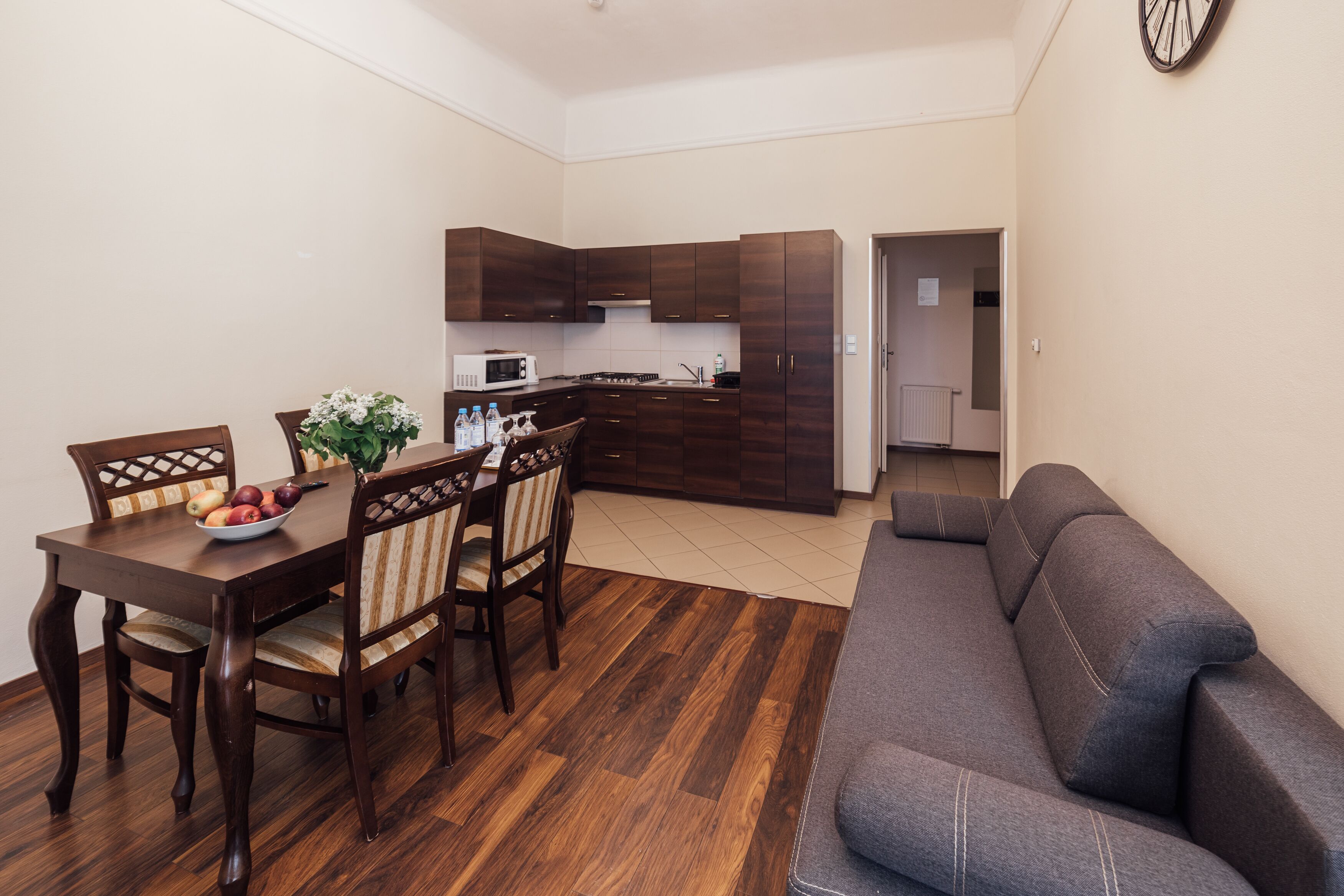Een moderne woonkamer met een grijze bank en een houten eettafel met stoelen.