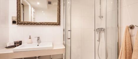 Une salle de bain moderne avec une douche à parois de verre, un lavabo blanc et un grand miroir décoratif.