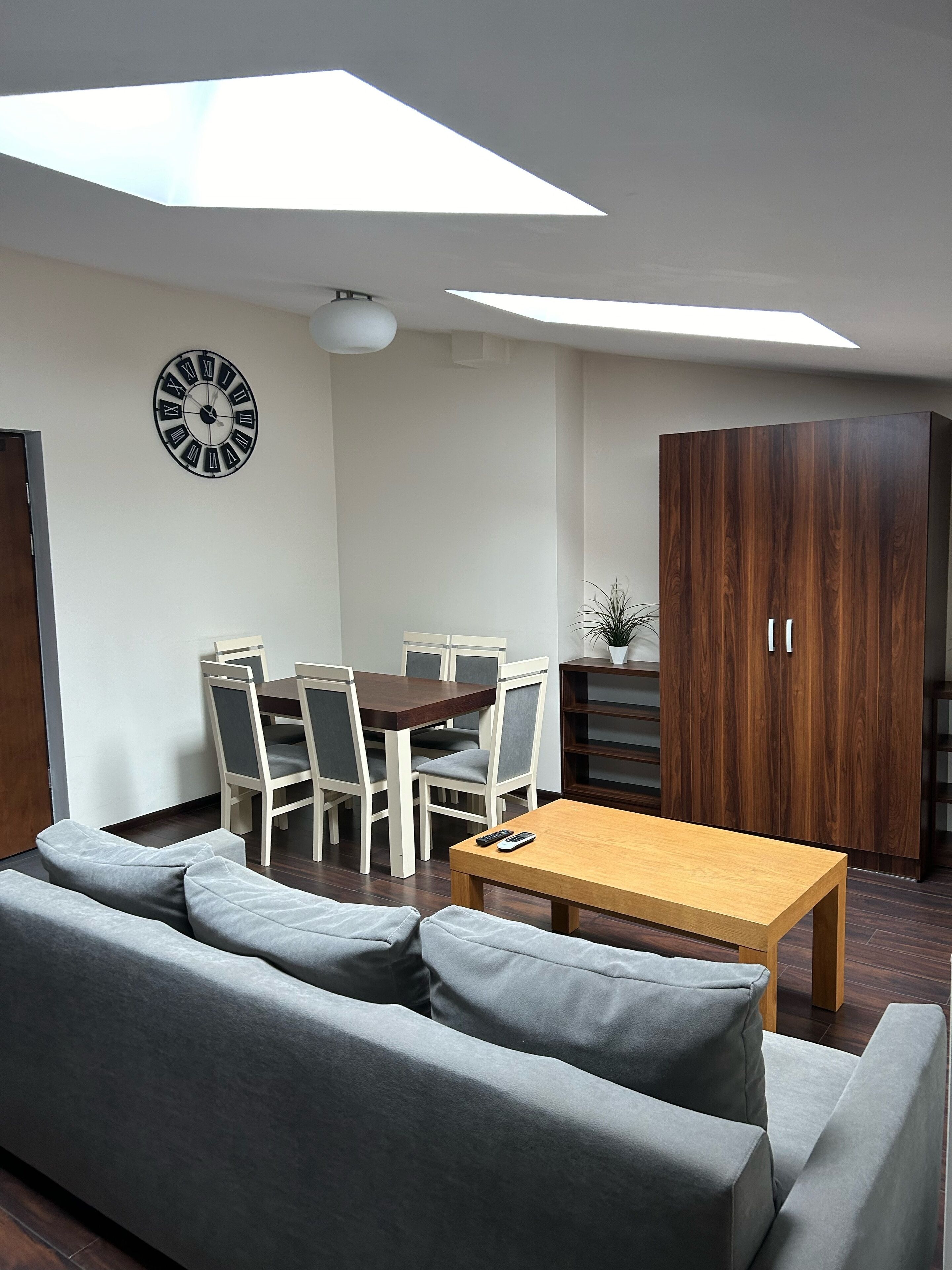 Una sala de estar moderna con comedor, un aparador de madera grande y un tragaluz.
