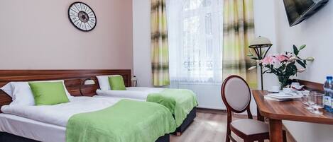 Habitación de hotel con dos camas, un escritorio con silla, un reloj en la pared y una ventana con cortinas.