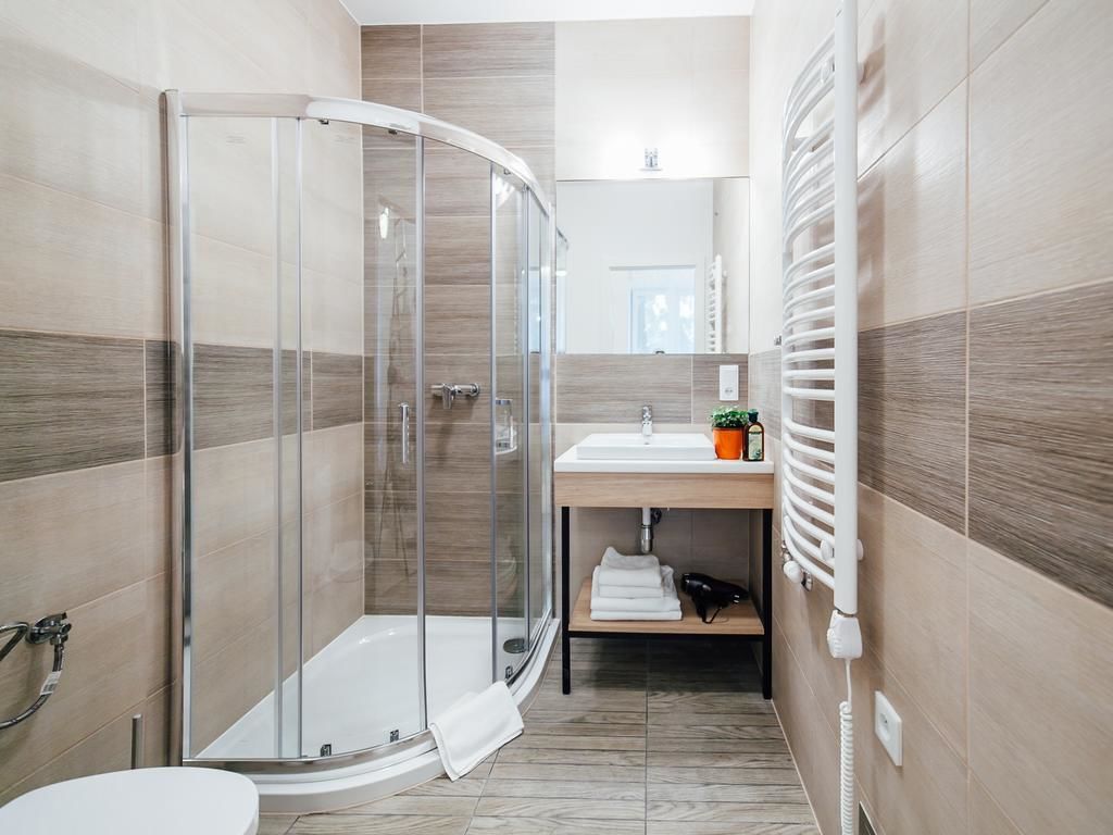 A modern bathroom with a glass shower enclosure, a sink with a mirror, and a towel rack.