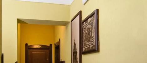 A hallway with a patterned floor, a wooden door at the end, and framed pictures on the walls.