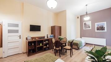 Una habitación de hotel compacta con kitchenette, comedor, cama y televisor.