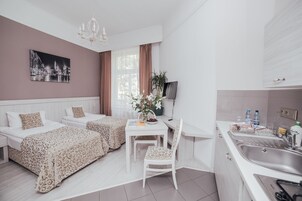 Una habitación de hotel moderna con comedor, dos camas, escritorio y kitchenette.