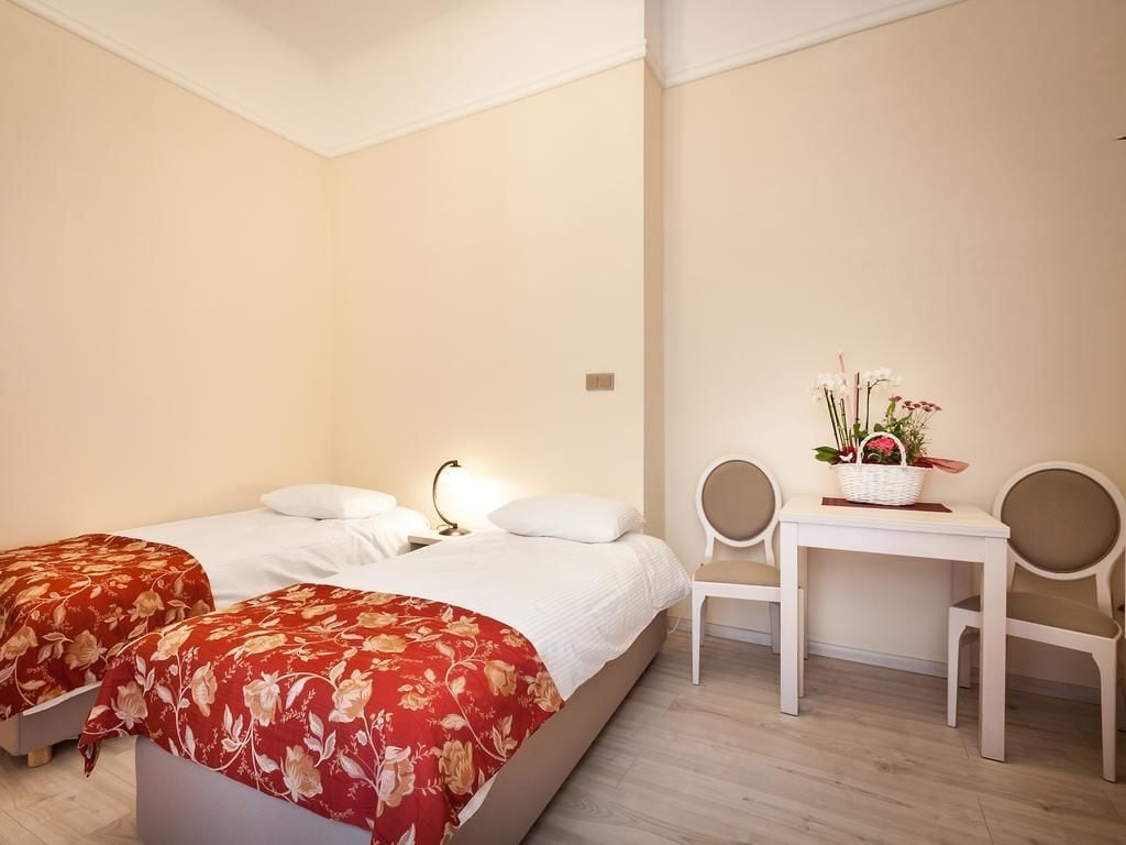 A bedroom with two beds, a desk, and chairs.