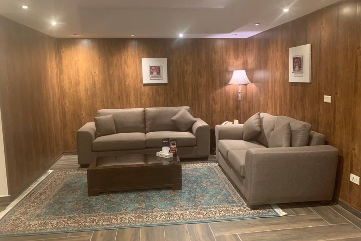 A modern living room with two sofas, a coffee table, and a lamp.