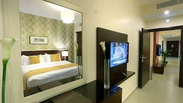 Habitación de hotel con cama, televisión, espejo y escritorio.
