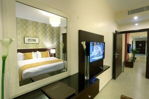 Habitación de hotel con cama, televisión, espejo y escritorio.