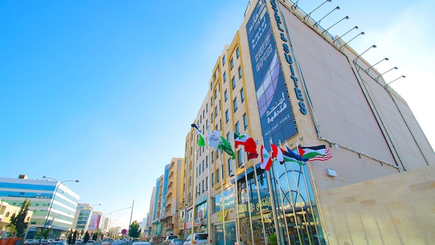 A hotel with multiple floors, large windows, and flags. - City Rose Hotel Suites (Amman)
