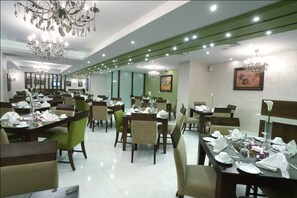 Un restaurante con varias mesas, sillas, candelabros y obras de arte enmarcadas en las paredes.