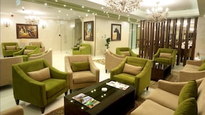 A spacious lobby with green and beige armchairs, a central coffee table, and a chandelier. - City Rose Hotel Suites (Amman)