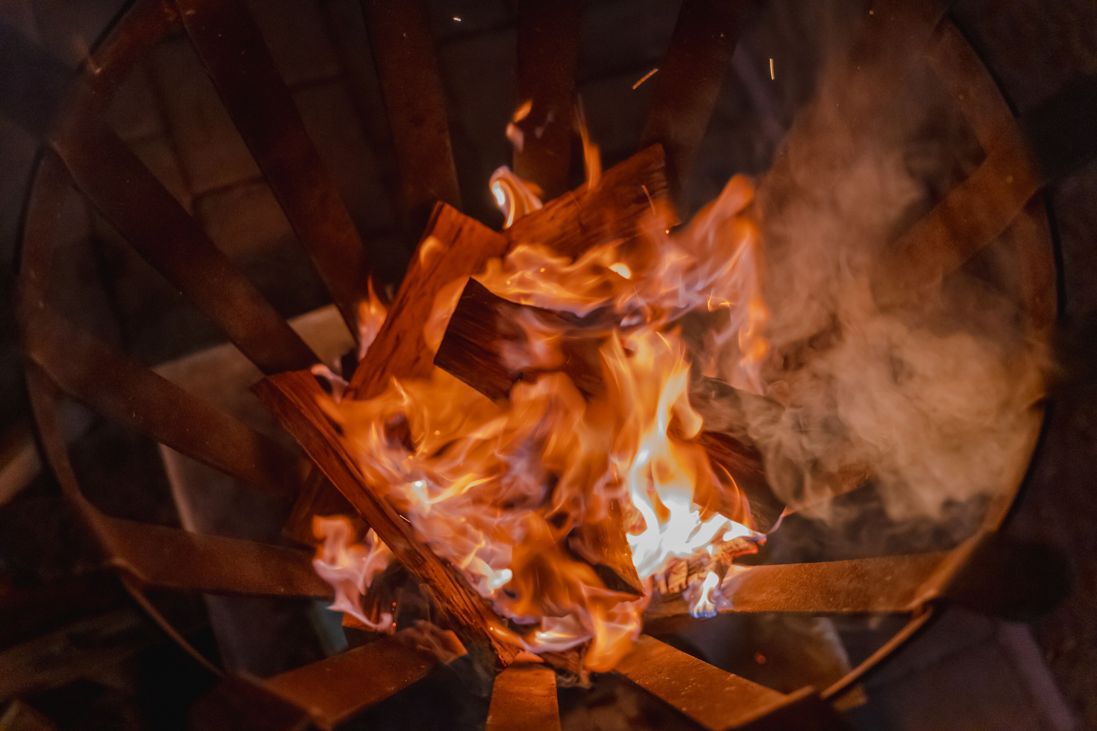 Un primo piano di un fuoco che arde in una grata metallica circolare.
