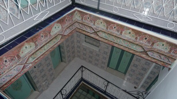 A corner of a building with ornate tile work and metal railings. - Hotel Aday (Marrakech)