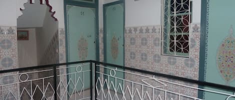 Una escalera con barandillas de metal ornamentadas y puertas con diseños decorativos.