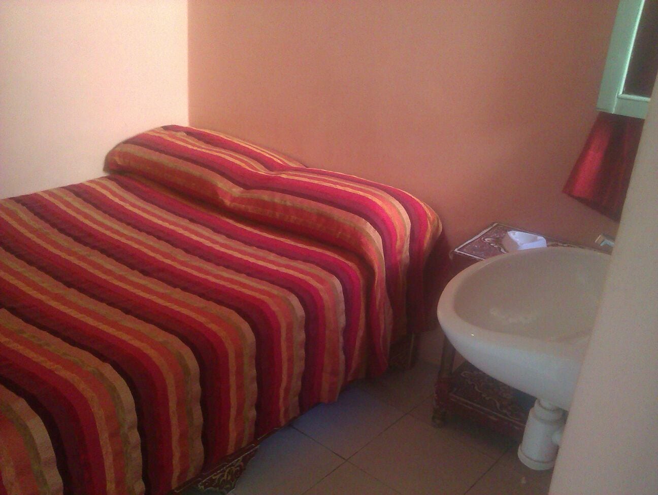 Una habitación pequeña y funcional con cama y lavamanos.