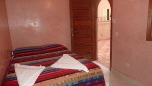 A bedroom with a bed, a door, and a view of an outdoor area. - Hotel Aday (Marrakech)