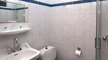 A bathroom with a sink, mirror, toilet, and shower.