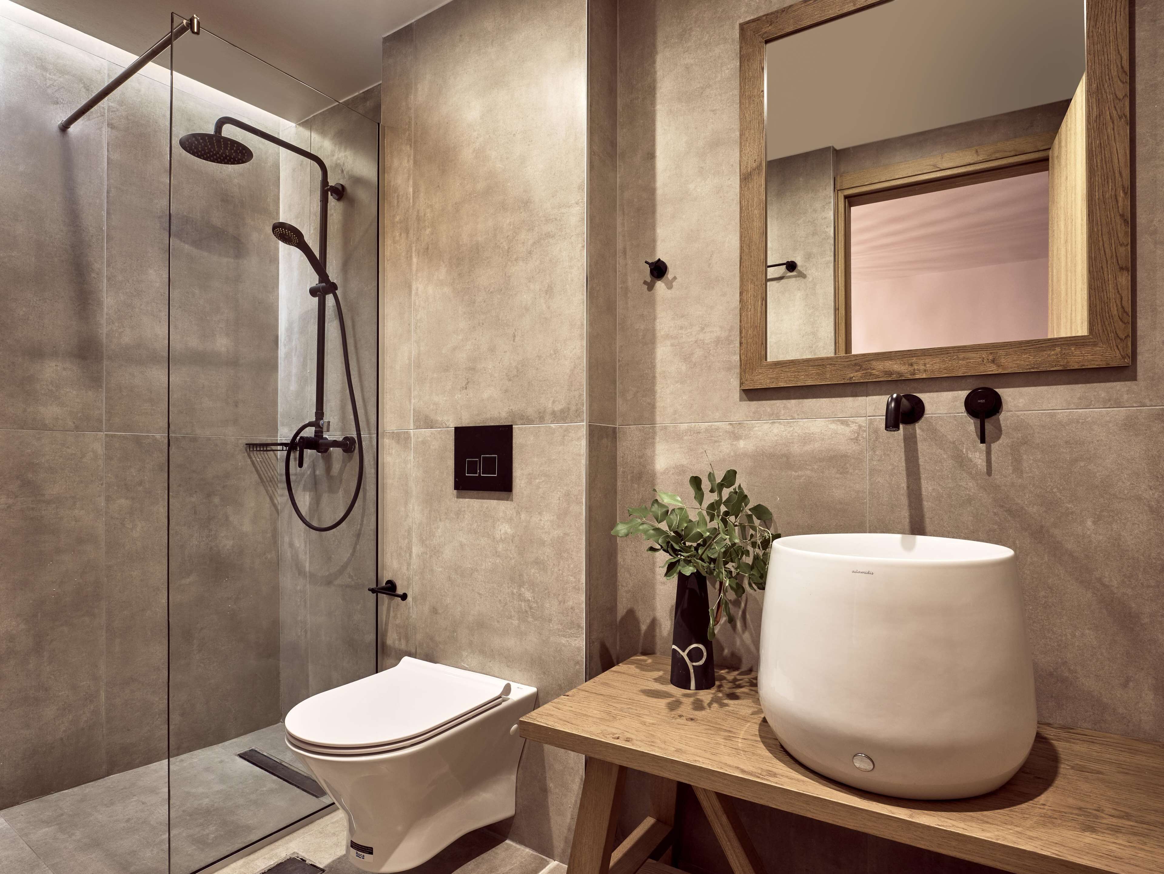 A modern bathroom with a glass-enclosed shower, a toilet, and a large sink with a mirror above it.