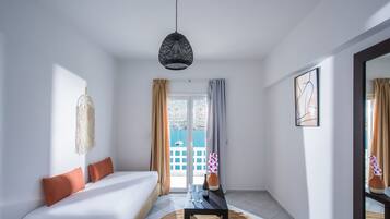 Una habitación de hotel moderna con una cama, una mesita con vasos y una botella, un tapete tejido y un espejo grande.