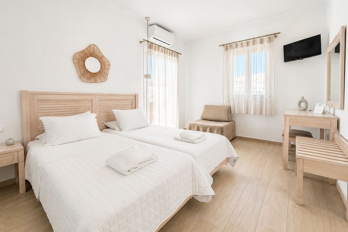 Une chambre d’hôtel avec deux lits, une télévision, un bureau et une chaise.