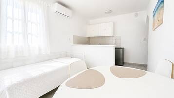 Una habitación funcional con cama, kitchenette y comedor.