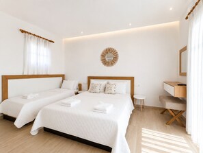 A hotel room with two beds, a desk, a small stool, a round mirror, and a wall-mounted light fixture. - Cyclades Blue (Mykonos)