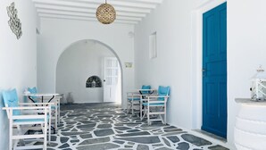 A white interior with stone flooring, blue doors, and white furniture. - Cyclades Blue (Mykonos)