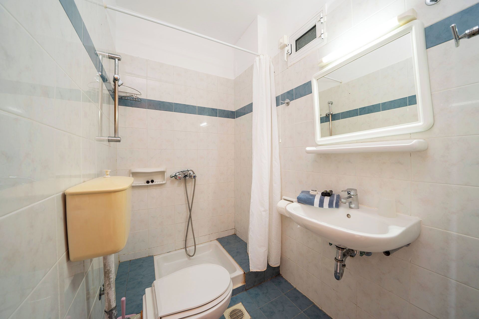 Un baño con inodoro, lavamanos, ducha y espejo.