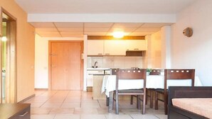 A compact hotel room with a bed, a small table, and a kitchenette. - Catalonia Park Apartments (Salou)