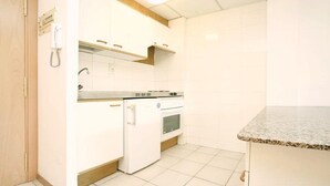 A kitchen with white cabinets, a built-in oven, and a granite countertop. - Catalonia Park Apartments (Salou)