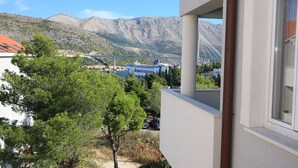 A balcony with a view of a mountainous landscape, a bridge, and a cruise ship in the distance. - Villa Erna (Dubrovnik)