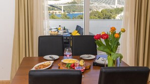 A dining table set with plates, glasses, and a vase of flowers. - Villa Erna (Dubrovnik)