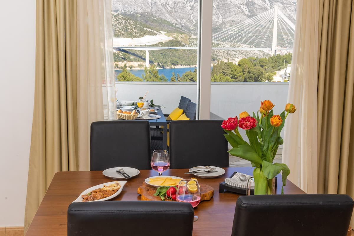 A dining table set with plates, glasses, and a vase of flowers.