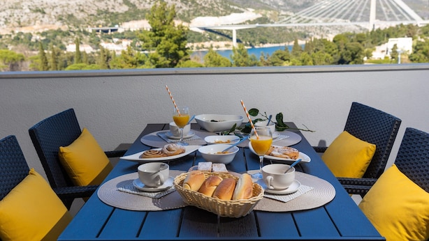 A table set for breakfast with a scenic mountain and bridge view. - Villa Erna (Dubrovnik)
