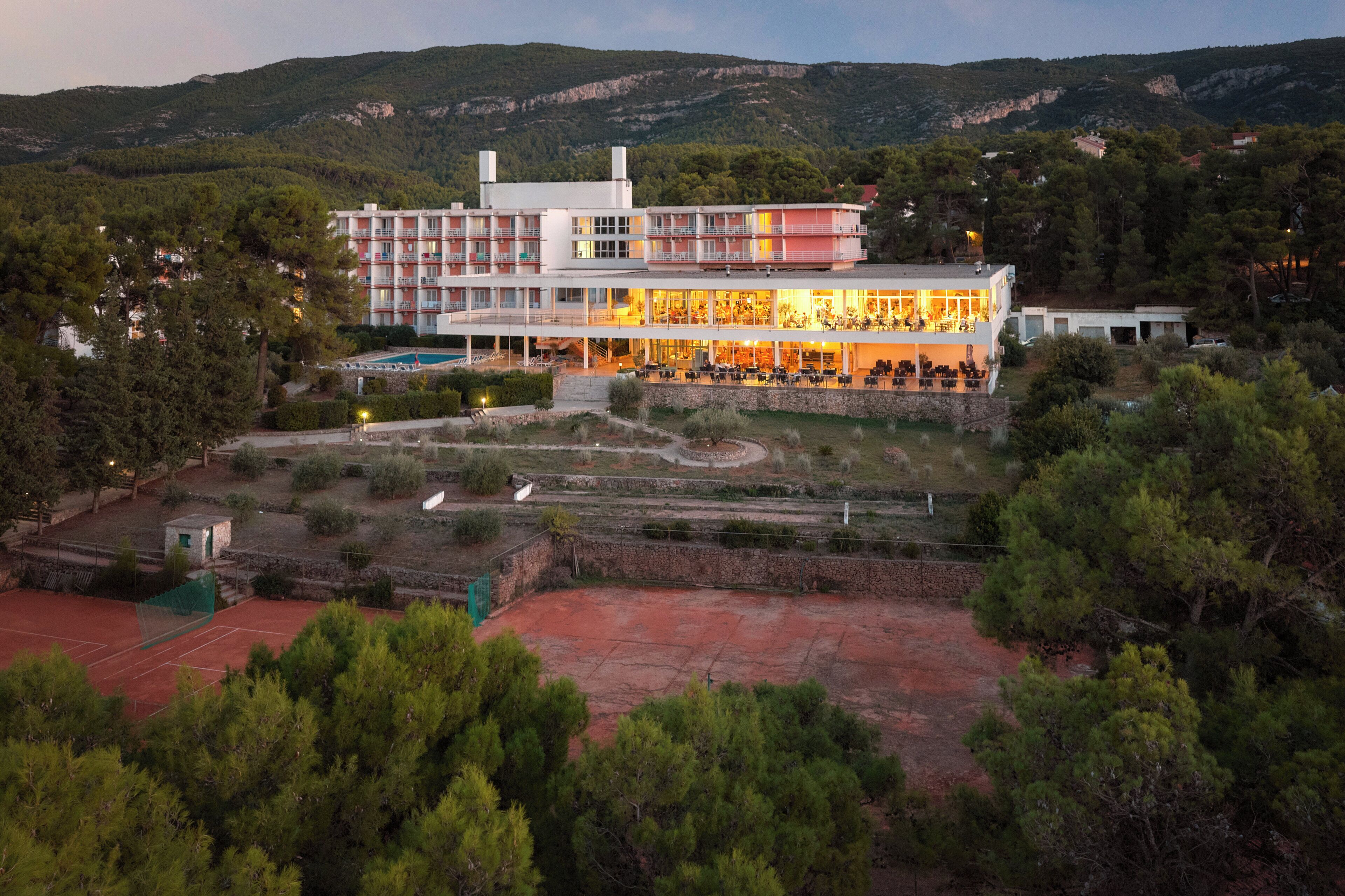 A hotel with multiple floors, outdoor swimming pool, and landscaped gardens.