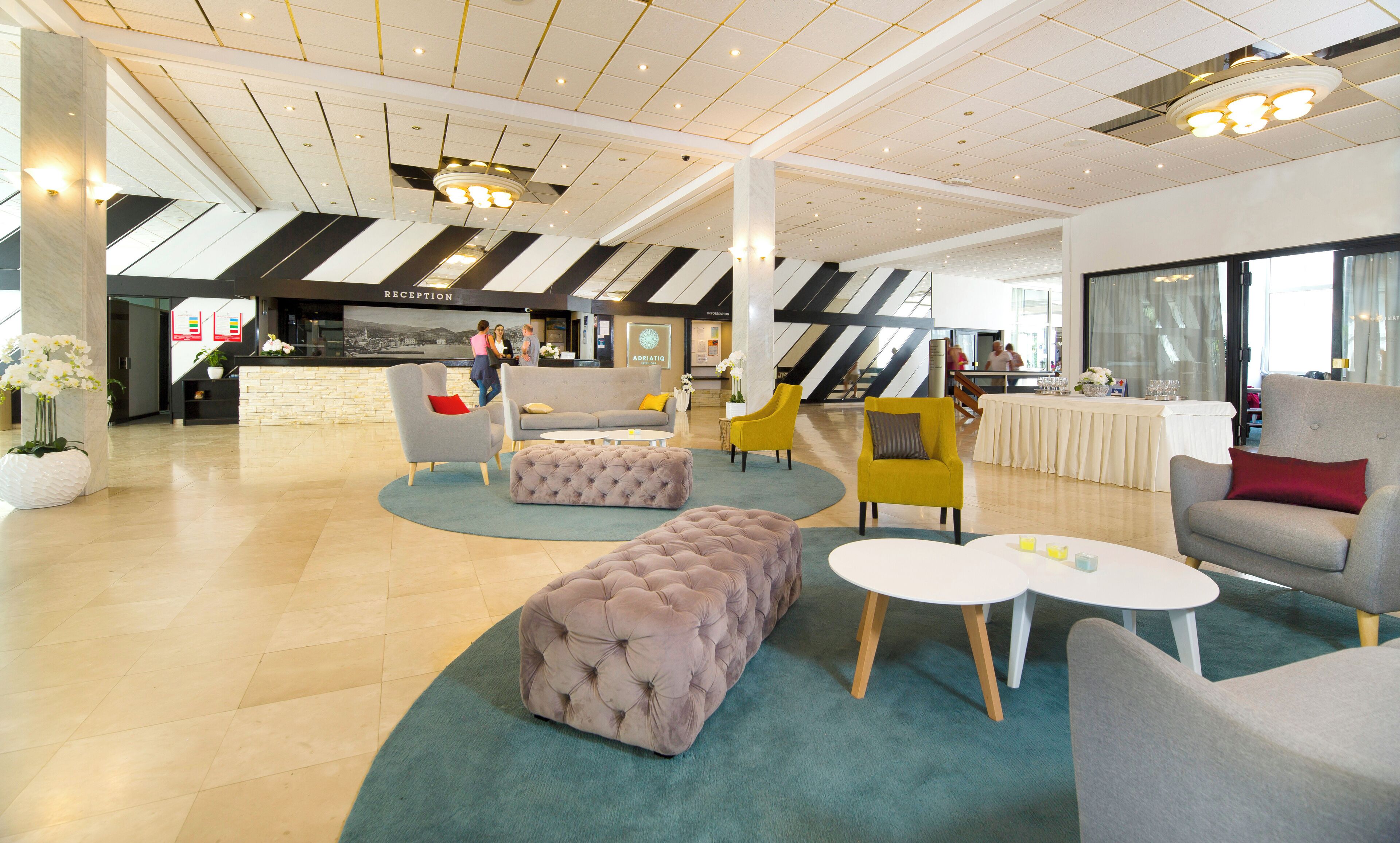 A spacious lobby with a reception desk, seating area, and a staircase.