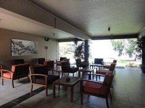 A covered outdoor seating area with multiple tables and chairs, a large painting on the wall, and potted plants. - Ekho Safari Tissa Hotel (Thissamaharama)