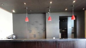 Una zona d'entrada moderna amb un taulell fosc, il·luminació penjant vermella i una làmpada fixada a la paret.