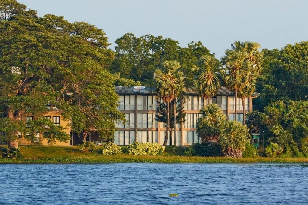 A building with a modern architectural style, surrounded by lush greenery and a body of water.