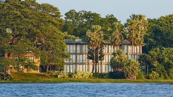 A building with a modern architectural style, surrounded by lush greenery and a body of water.
