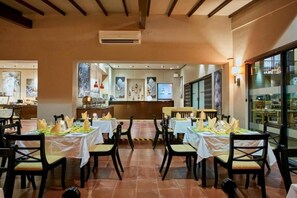 Um restaurante com mesas postas para refeições, cadeiras e um balcão.