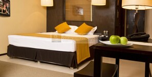 A hotel room with a bed, a nightstand, a lamp, and a plate with apples. - Ekho Safari Tissa Hotel (Thissamaharama)