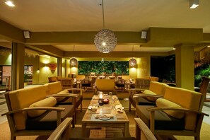 A dining area with yellow chairs, a central table set for a meal, and a decorative hanging light fixture. - Ekho Safari Tissa Hotel (Thissamaharama)
