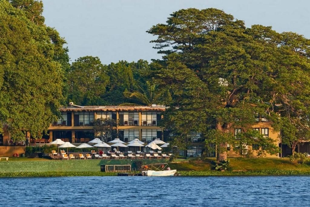Un hotel frente al agua con terraza al aire libre y un barco amarrado cerca.