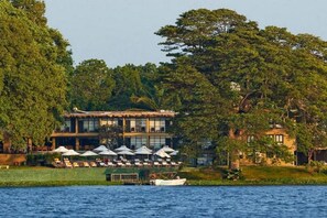 Un hotel frente al agua con terraza al aire libre y un barco amarrado cerca.