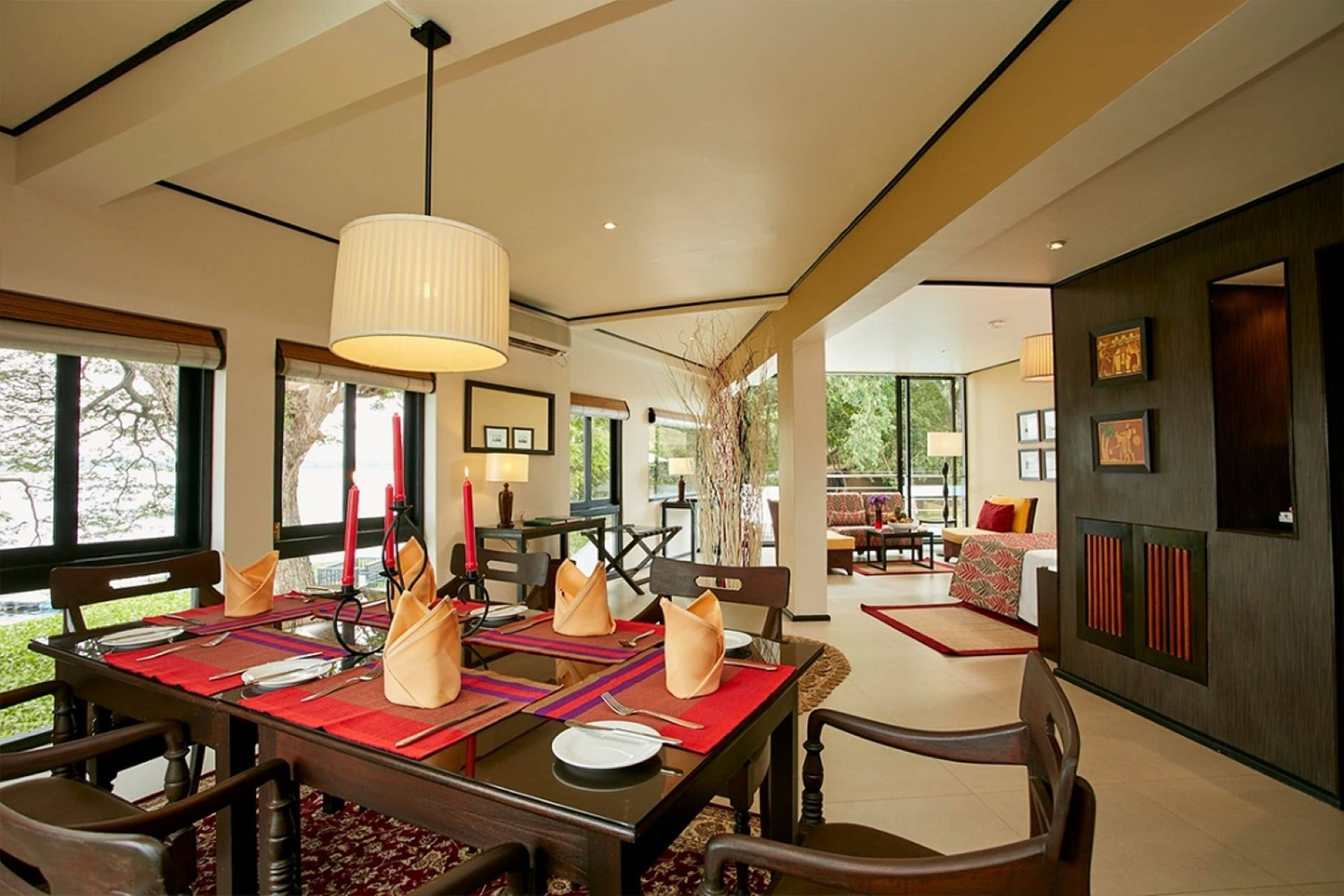 A dining area with a table set for four, a chandelier, and a view of the outdoors.