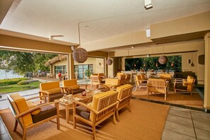 Un amplio espacio exterior con comedor, muebles de madera y vista al mar.