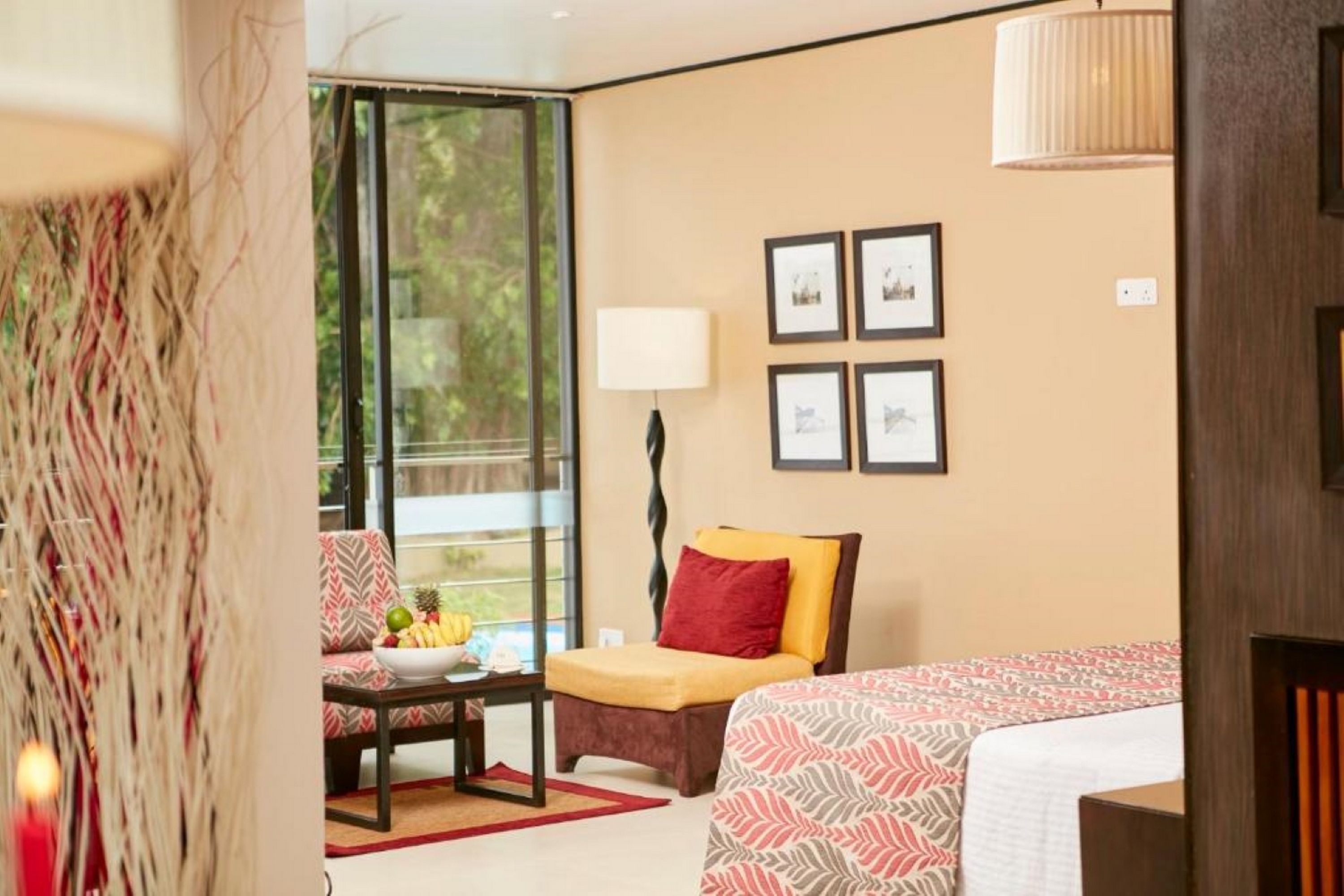 A hotel room with a bed, a sofa, a table with fruit, and a window with a view.