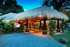 A resort with thatched-roof structures, a signboard, and potted plants. - Ekho Safari Tissa Hotel (Thissamaharama)